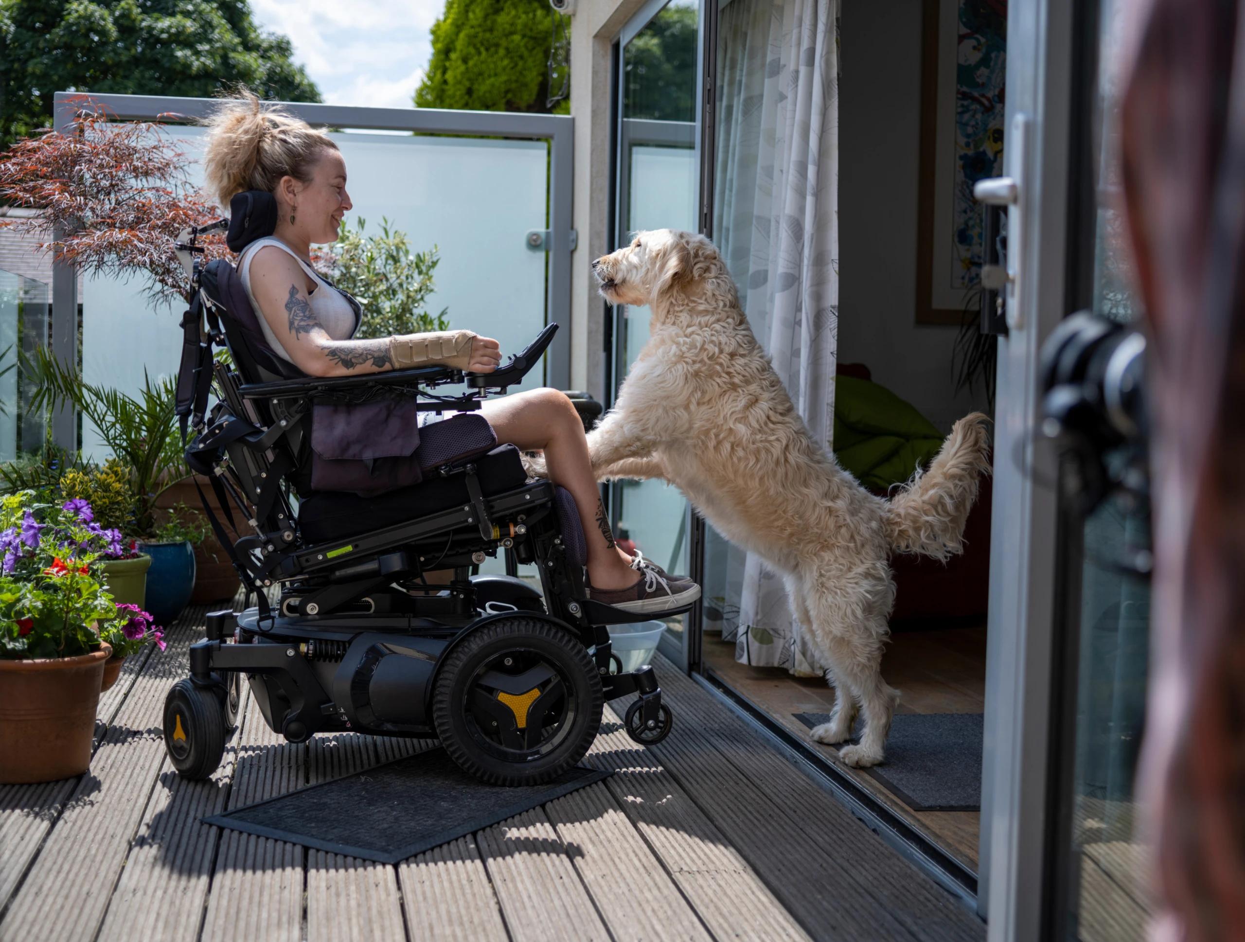 Kvinna i elektrisk rullstol med hund.